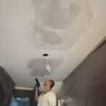 A Painter Drying A Plaster Repair on the ceiling with a Heat Gun