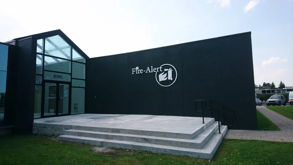 Modern commercial building exterior featuring matte black painted architectural wall panels, glass atrium entrance, and clean Fire-Alert signage completed by painters in Ottawa.