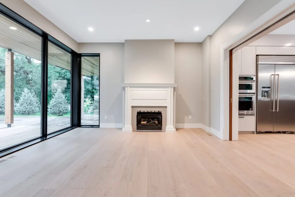 Spacious modern Ottawa living room featuring warm greige painted walls, a crisp white painted fireplace mantel, a smooth flat ceiling, and bright floor-to-ceiling glass patio doors.