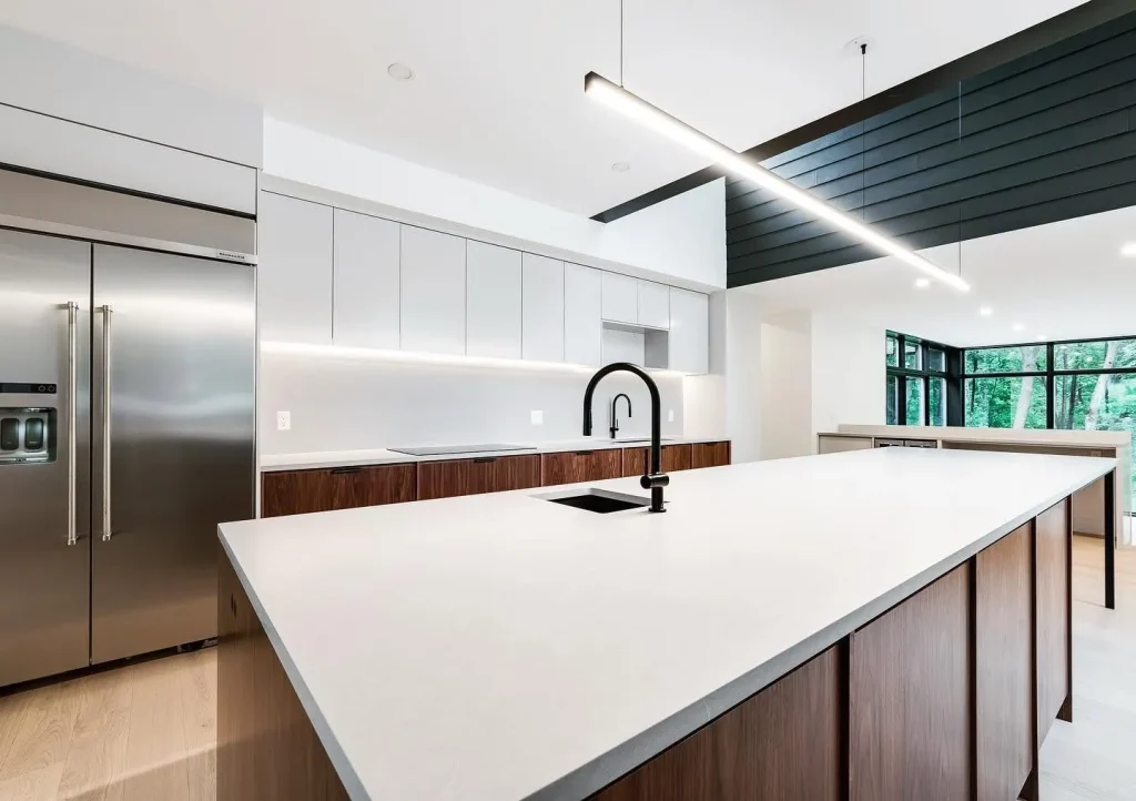 Contemporary open-concept kitchen featuring smooth off-white painted walls, seamless ceiling finish, and dark wood accents in an Ottawa home.